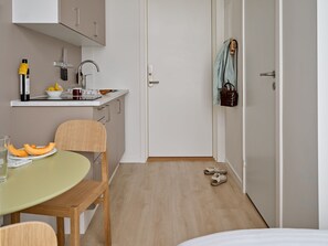 A compact kitchen with a sink, a small countertop, and a dining area with a table and chairs.
