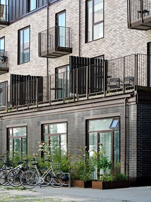 A modern building with multiple balconies, large windows, and a row of bicycles parked outside.