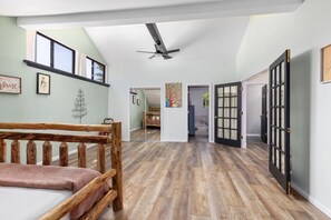 Ein geräumiges Zimmer mit einer hölzernen Bank, einem Deckenventilator und einem großen Spiegel, der einen weiteren Raum widerspiegelt.