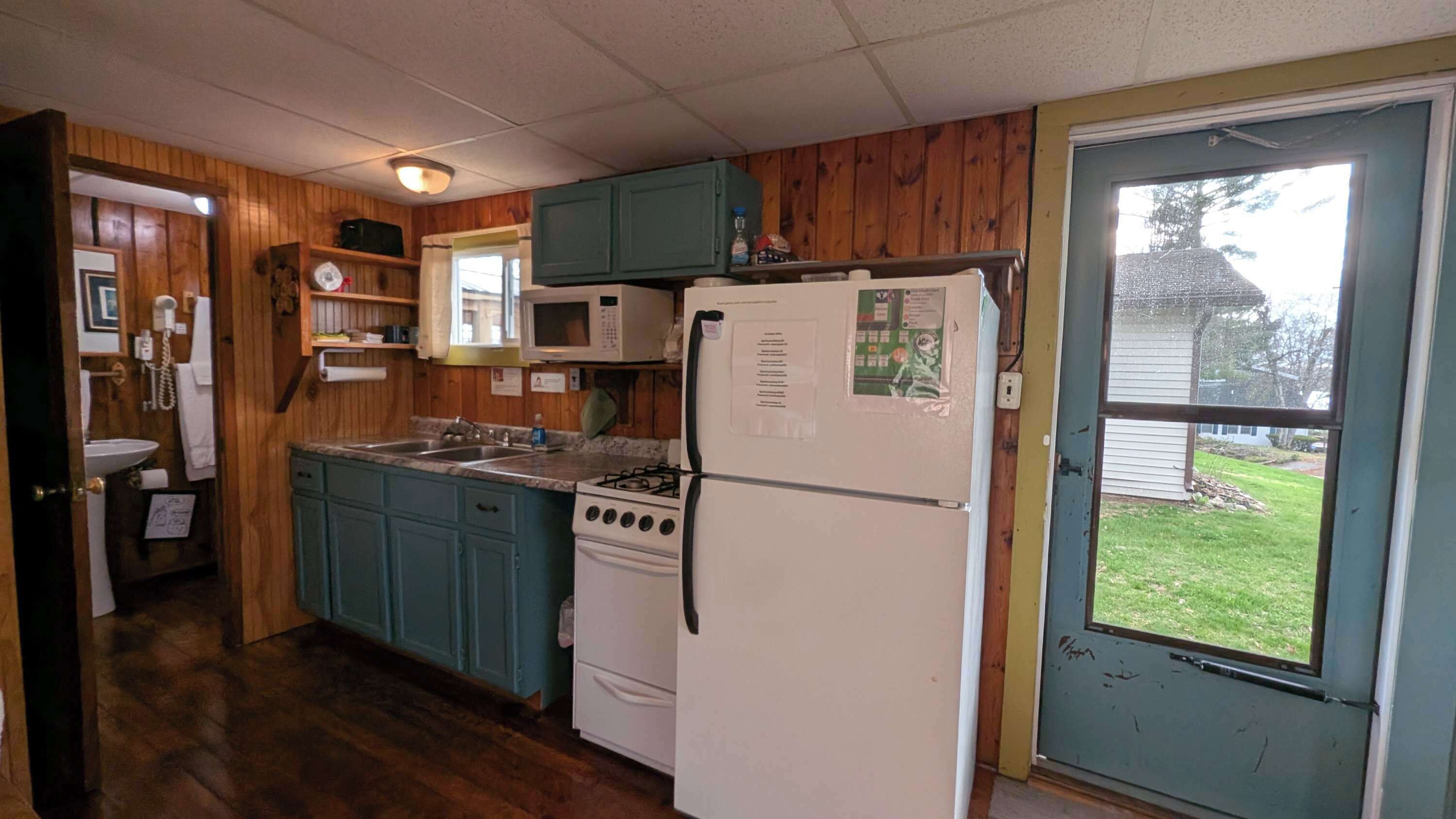 A compact kitchen with wooden cabinets, a stove, a refrigerator, and a microwave.