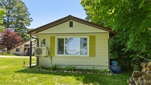 A single-story house with a number '4' on the front, a small porch, and a yard with a flag. - 1BR Cozy Cabin- Small walk from Chippewa Lake (Chippewa Lake)