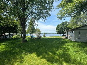 Ett grönområde med ett litet förråd, en gunga och utsikt över en sjö.