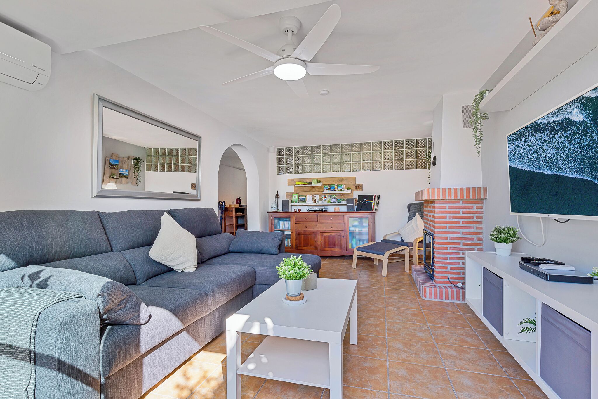 A modern living room with a grey sofa, a white coffee table, and a TV mounted on the wall.