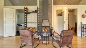 A cozy room with a fireplace, two leather chairs, a small table, and a wooden floor. - Beautiful home in Henån with kitchen (Henån)