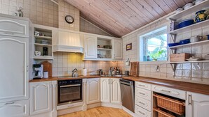 A kitchen with white cabinetry, a wooden countertop, an oven, a dishwasher, and a window with a view of greenery. - Beautiful home in Henån with kitchen (Henån)