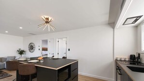 A modern kitchen with a central island, bar stools, a dining area, and a built-in oven. - The Fairlady - Lake Views, Executive, Sleeps 4 (Rotorua)