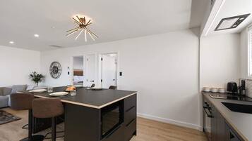 A modern kitchen with a central island, bar stools, a dining area, and a built-in oven.
