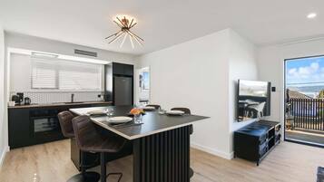A modern kitchen with a central island, bar stools, and a dining area with a TV.