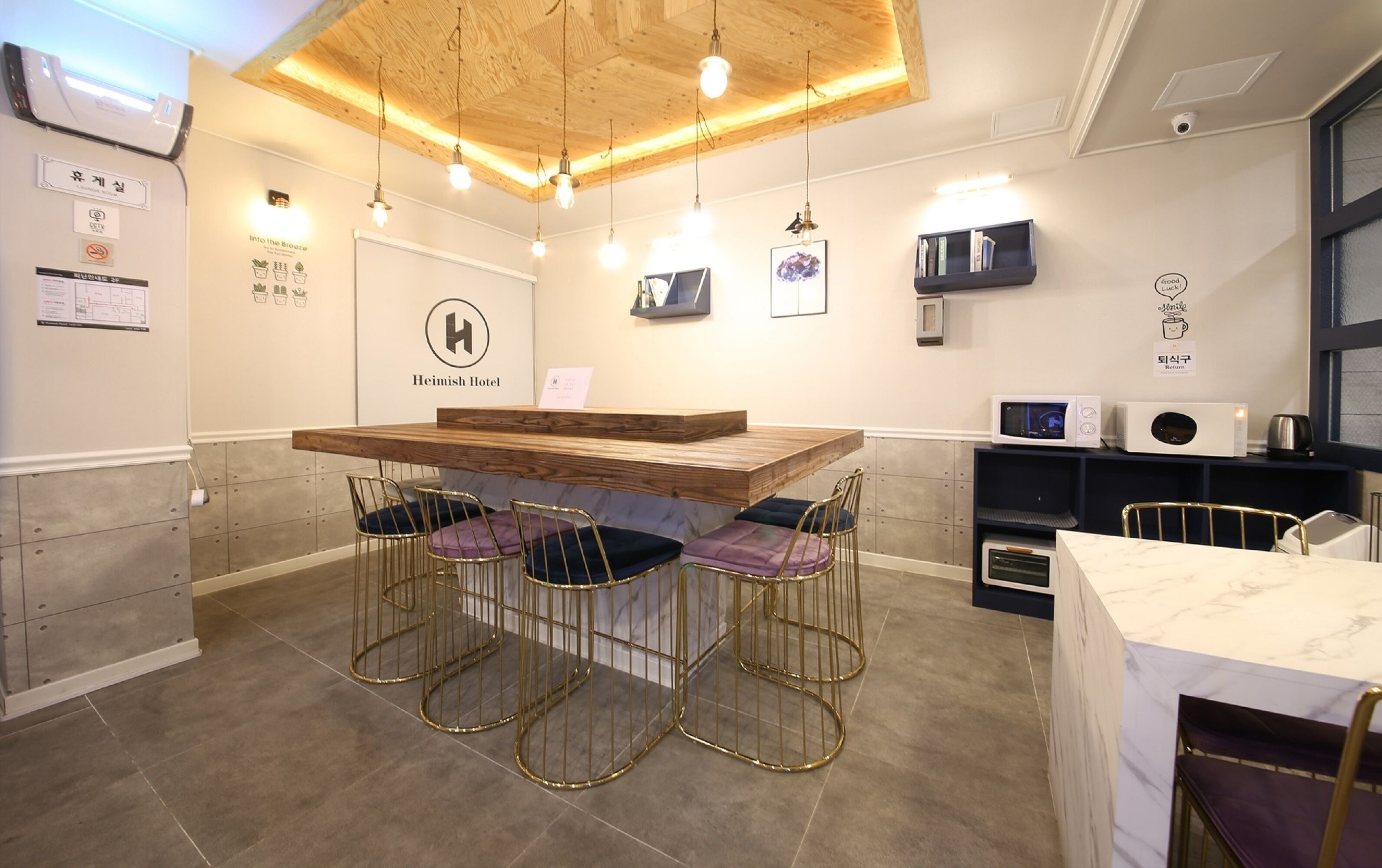 A modern kitchen with a wooden table and bar stools, a microwave, and a coffee machine.