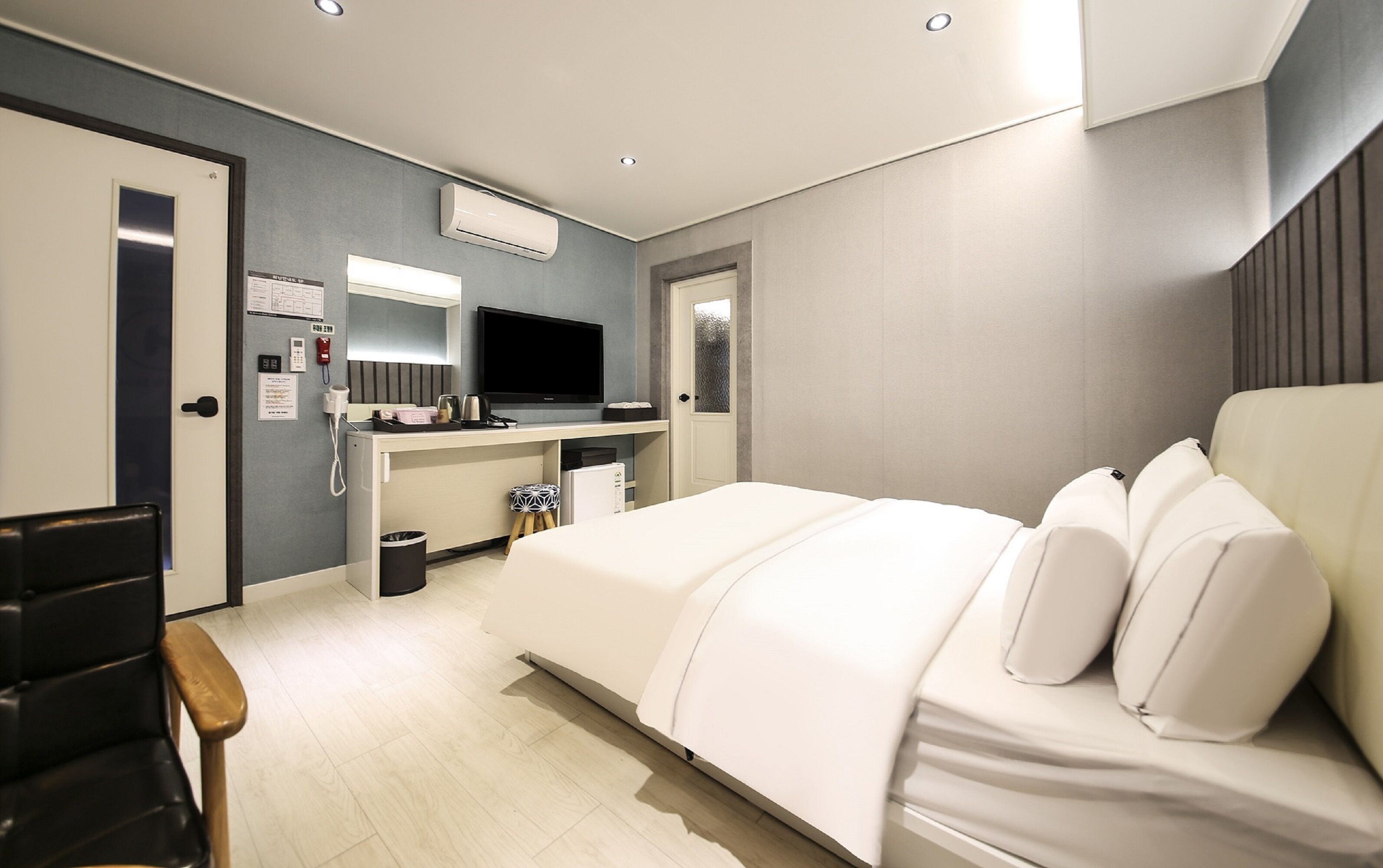 Ett modernt hotellrum med en säng, ett skrivbord med en dator, en TV och en minibar.
