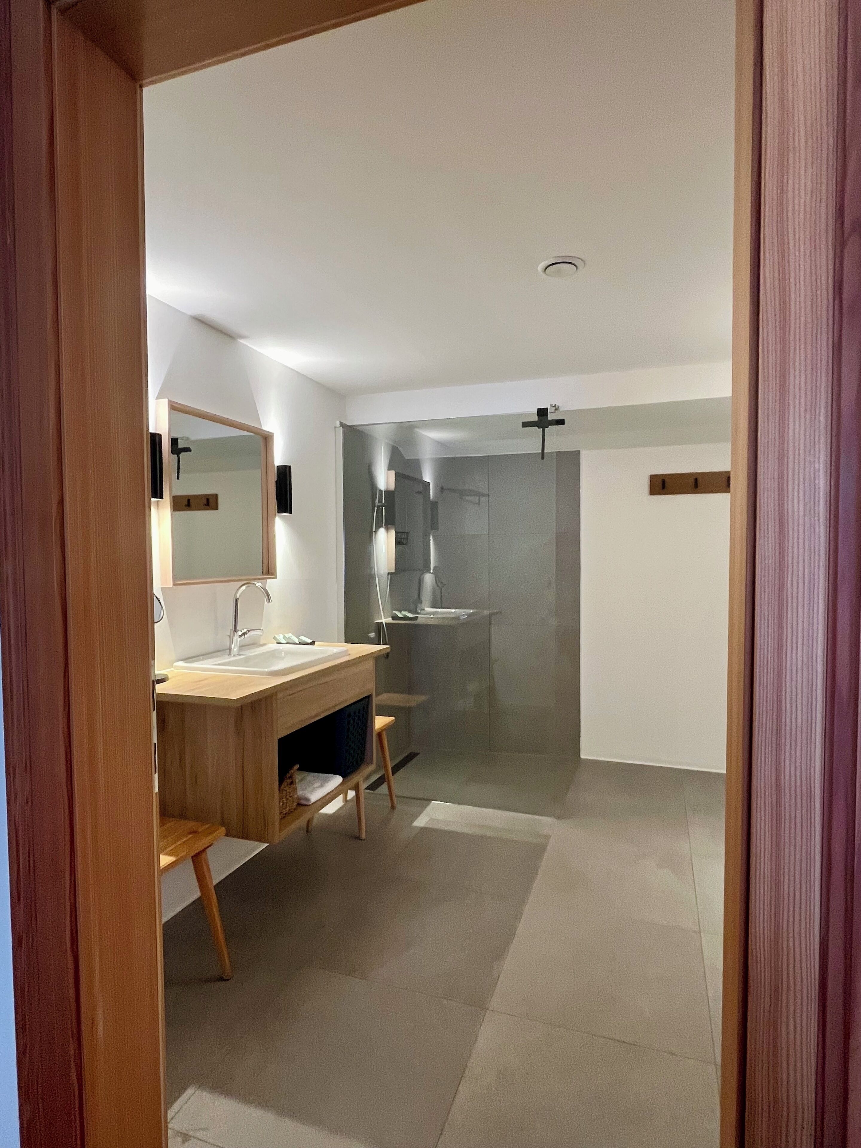 A modern bathroom with a wooden vanity, a glass shower enclosure, and a visible towel rack.