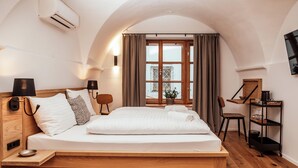 Une chambre moderne avec un lit en bois, une petite table de chevet, une chaise, un bureau avec une chaise, une étagère avec des verres et une fenêtre avec des rideaux.