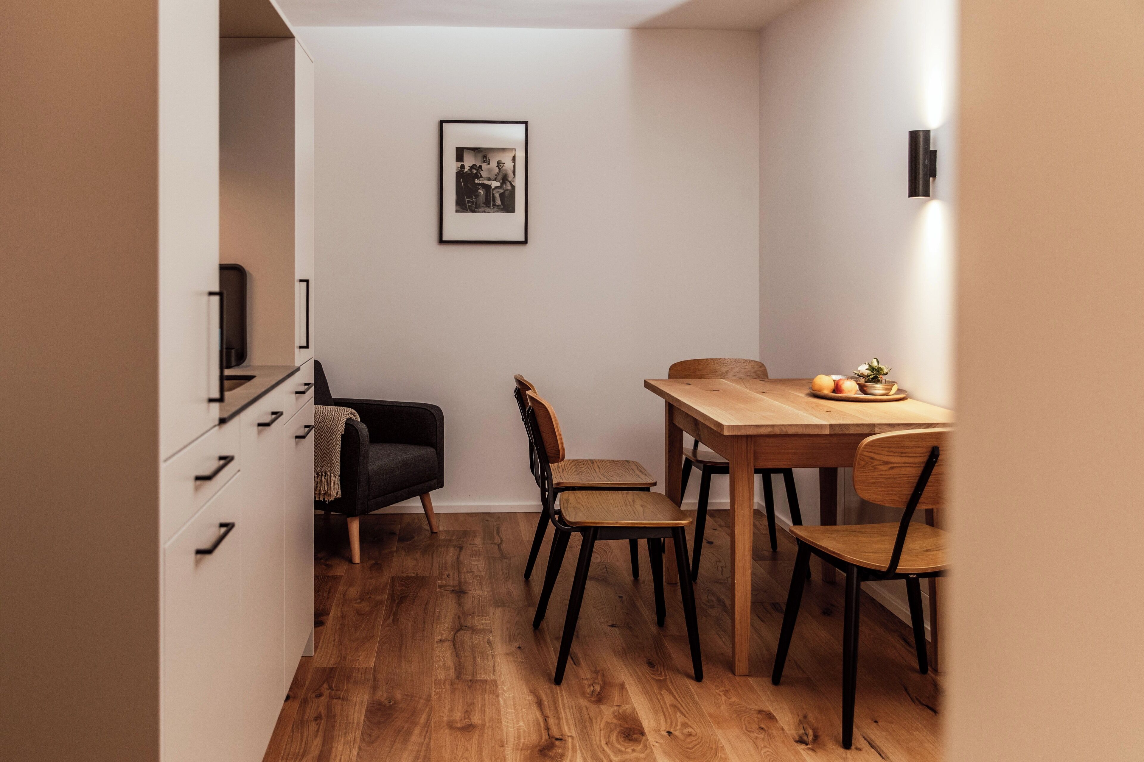 Ein gemütlicher Essbereich mit einem Holztisch und Stühlen, einem schwarzen Stuhl und einem gerahmten Bild an der Wand.