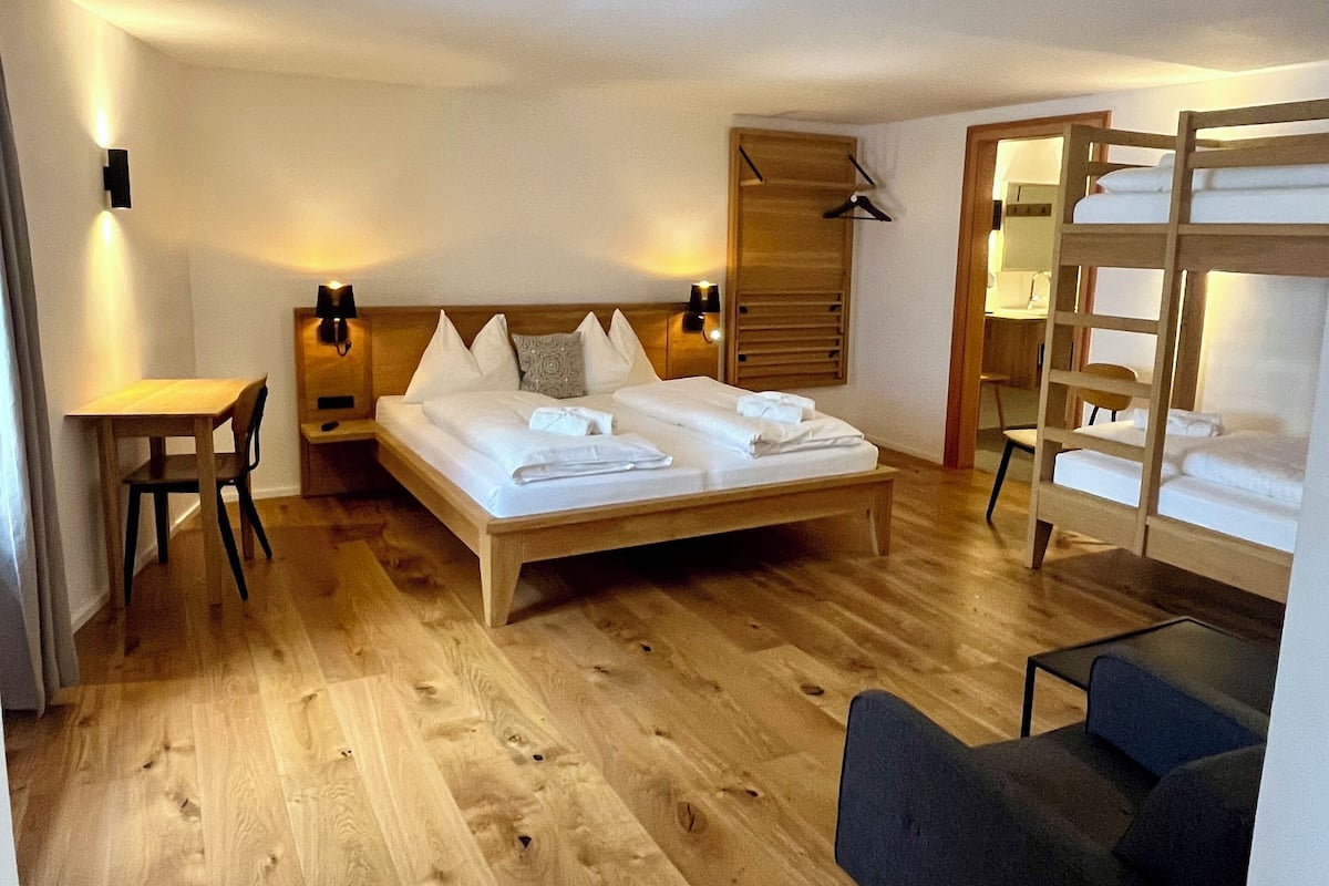 Un dormitorio con una cama de madera, un escritorio, una silla, un sofá y un armario.