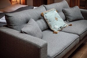 A grey sofa with a light blue throw pillow and tassels, and a matching pillow on a wooden floor. - the salt townhouse (Hallein)