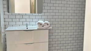A bathroom with a white vanity, black marble floor, and a white brick-patterned wall. - La Pléïade Dorée - Hyper Centre, Avec Cours Privative. Animaux Acceptés ! (Amiens)
