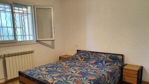 Makuuhuoneessa on sänky, kaksi yöpöytää, patteri ja ikkunassa on sälekaihtimet.