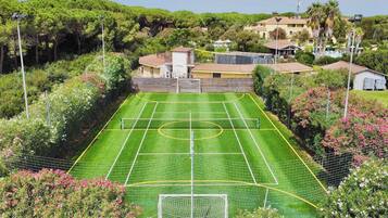 A soccer field surrounded by lush greenery and residential buildings.