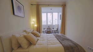 Une chambre d’hôtel avec un lit, des lampes de chevet, une chaise et une vue sur la ville par la fenêtre.
