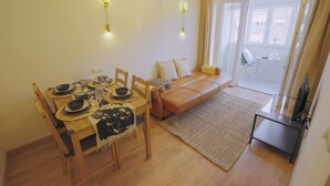 Un coin repas avec une table en bois dressée pour quatre personnes, un canapé et une table basse en verre.