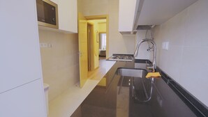 Une petite cuisine étroite équipée d’un four à micro-ondes, d’un évier et d’un petit plan de travail.