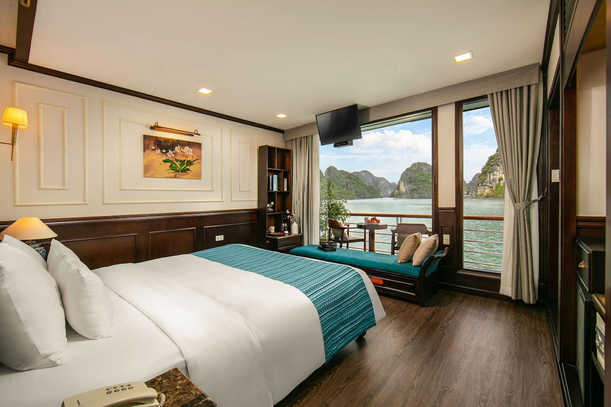 A hotel room with a large bed, a seating area by the window, and a view of a body of water.