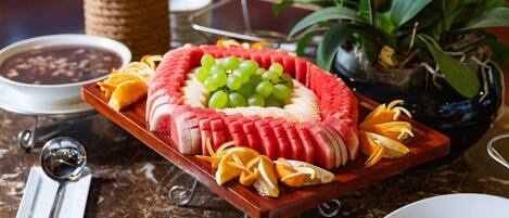 A fruit platter with watermelon, grapes, and oranges on a marble table.