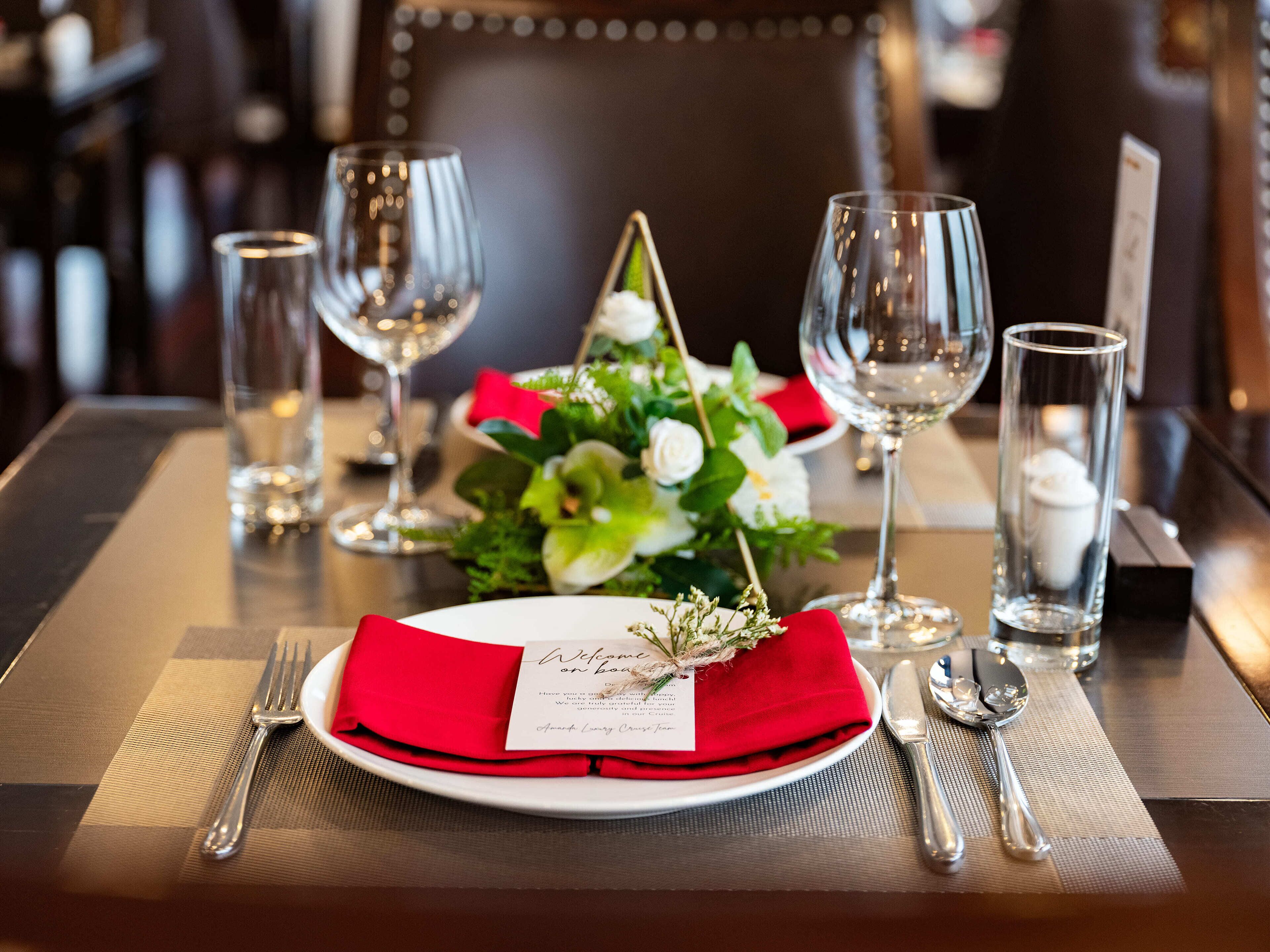 A dining table set with a red napkin, a white plate, and a menu card.