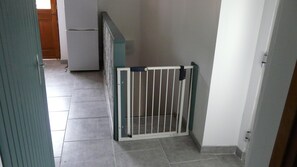 Un couloir avec une porte blanche, un réfrigérateur et un sol carrelé.