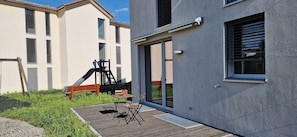 Un bâtiment moderne doté d’une terrasse en bois, d’un espace salon extérieur et d’un toboggan.