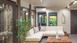 A modern living room with a sectional sofa, a coffee table, and a potted plant. - JAPAVISTA Hisho (Osaka)