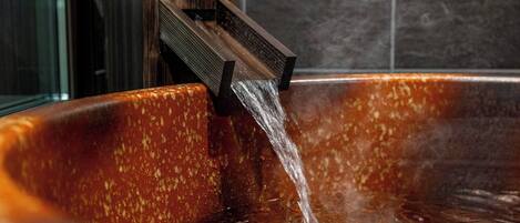 A hot tub with water flowing from a wooden structure.
