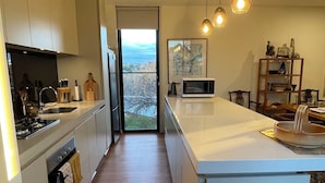 A modern kitchen with a large island, wooden flooring, and pendant lighting. - Cosy “Mod” in Clunes  (Clunes)