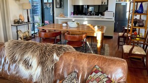 A modern kitchen with a central island, pendant lighting, and a dining area with leather chairs. - Cosy “Mod” in Clunes  (Clunes)