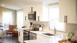 A modern kitchen with white cabinetry, stainless steel appliances, and a central island.