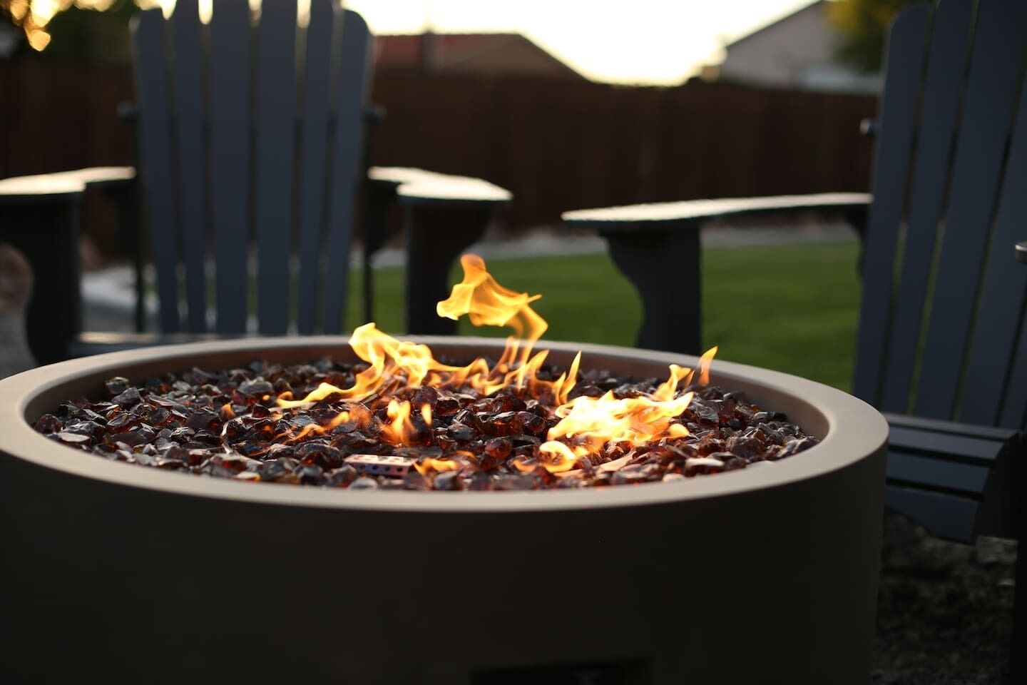 A circular outdoor fire feature surrounded by Adirondack chairs.