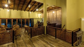A spacious indoor area with wooden flooring, high ceilings, and a seating area with chairs and tables. - Sigiriya Forest Edge By Marino Leisure (Avudangawa)