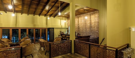 A spacious indoor area with wooden flooring, high ceilings, and a seating area with chairs and tables.