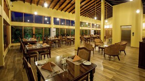 A spacious dining area with multiple tables and chairs, large windows, and a wooden ceiling. - Sigiriya Forest Edge By Marino Leisure (Avudangawa)