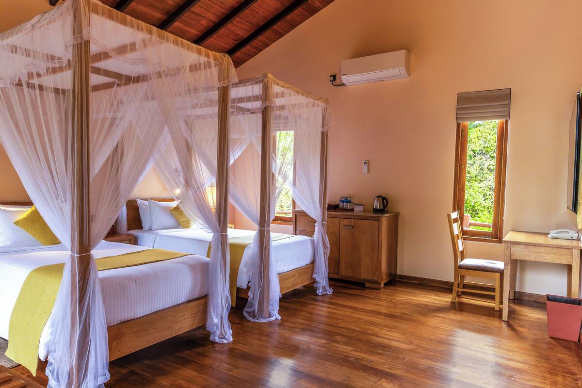 A room with a four-poster bed, a wooden desk, and a chair.
