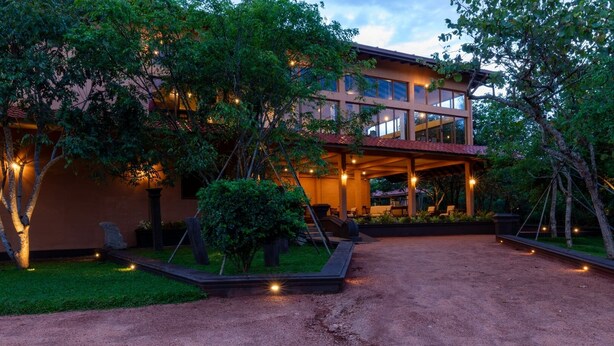 A modern building with a covered outdoor area, surrounded by trees and a gravel path. - Sigiriya Forest Edge By Marino Leisure (Avudangawa)