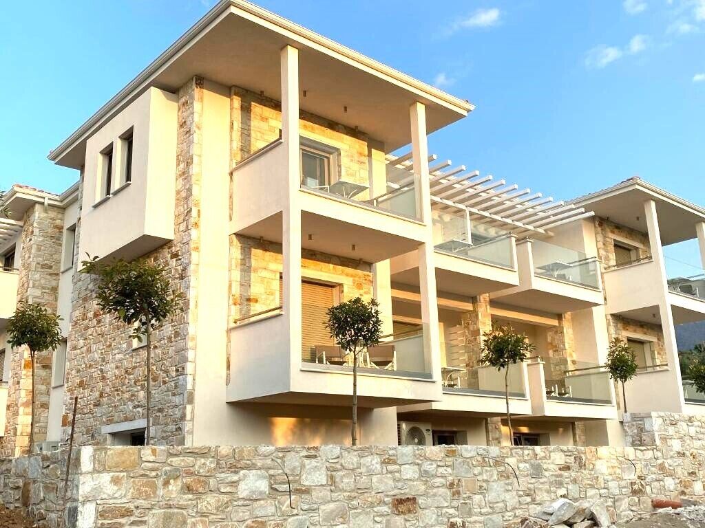 Un immeuble résidentiel à plusieurs étages, doté de balcons, d’une façade en pierre et surplombant un ciel dégagé.