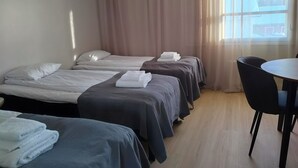 A hotel room with two single beds, a round table, and a chair. - Taiga Resort (Oulu)