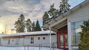 A building with a red door and large windows, surrounded by snow and trees. - Taiga Resort (Oulu)