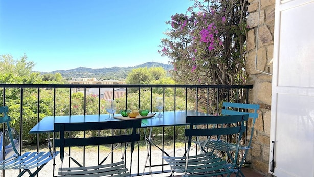 Ein Balkon mit Tisch und Stühlen, Blick auf die Landschaft und eine Steinmauer.