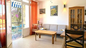 Ein gemütliches Wohnzimmer mit einer Couch, einem Holztisch und einem Deckenventilator.