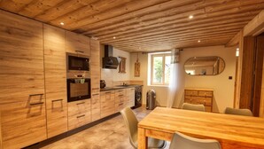 A modern kitchen with wooden cabinets, a dining table, and chairs. - Renovated apartment in central Morillon for 6 ppl. (Morillon Village)