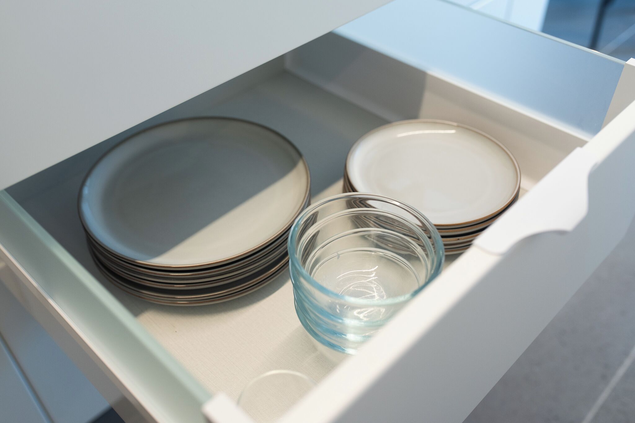 A drawer containing stacked plates and a glass.