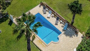 An aerial view of a rectangular swimming pool with a tiled deck, surrounded by a wooden deck and palm trees. - Traditional Algarve home with private pool, air con & solar, near Praia Marinha (Lagoa)