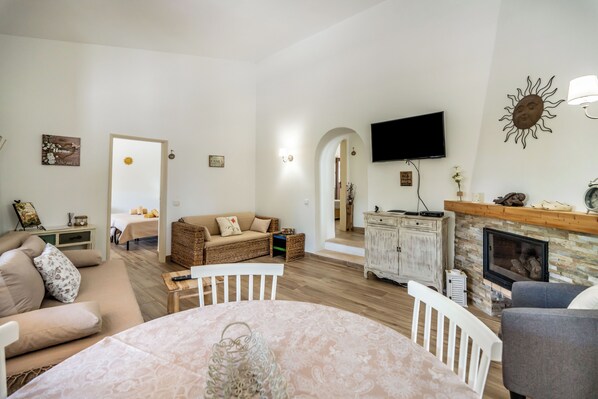 A living room with a fireplace, a television, and a dining area with a table and chairs.